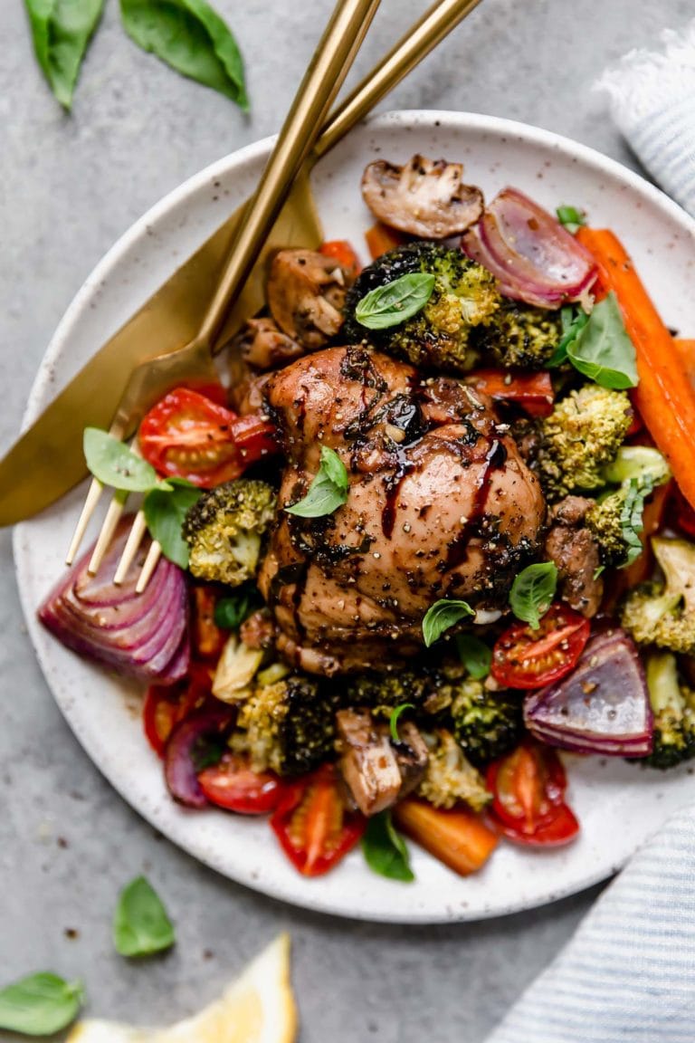 Overhead view serving of sheet pan balsamic chicken and veggies on plate with gold cutlery