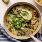 An overhead view of slow cooker white chicken chili in a cream bowl and topped with jalapeno and avocado slices