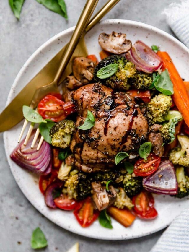 Overhead view serving of sheet pan balsamic chicken and veggies on plate with gold cutlery