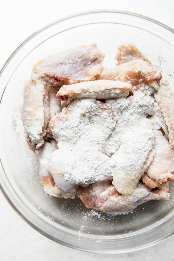 Raw chicken wings with baking powder and sea salt in a mixing bowl ready to be tossed together