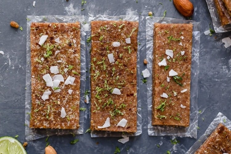 Three key lime energy bars lined up and topped with lime zest and coconut shreds