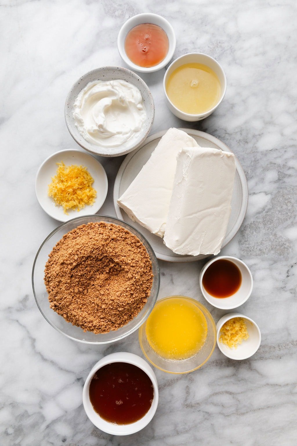 Overhead view of a variety of ingredients for No Bake Lemon Cheesecake Bars in different sized bowls. 