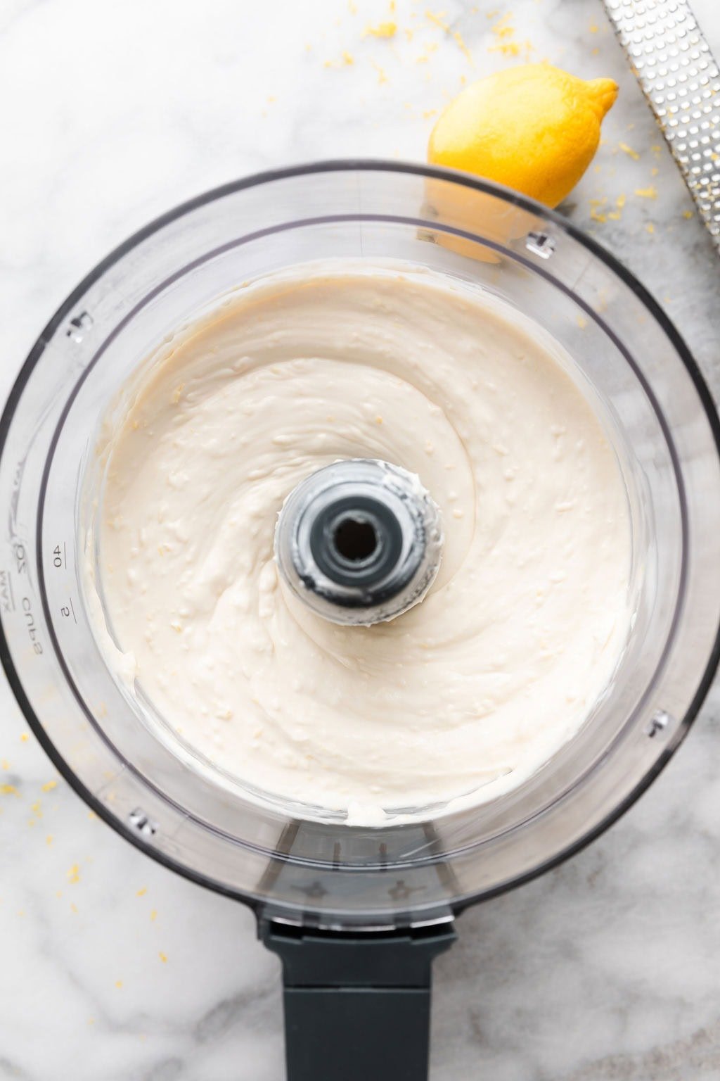 Overhead view of a food processor filled with lemon cheesecake filling 