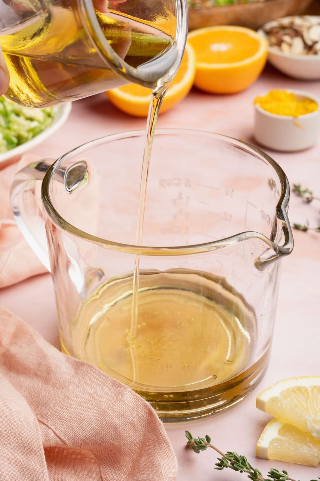 Olive oil being poured into a glass measuring cup.