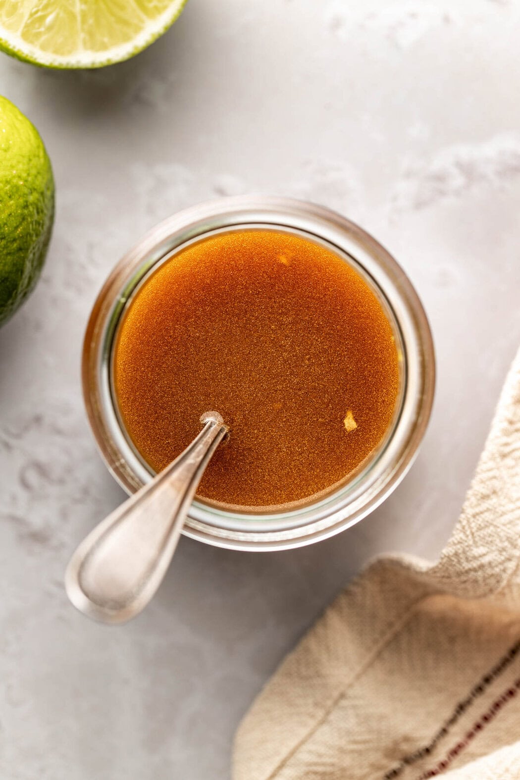 Overhead view of a glass jar filled with Sesame Ginger Dressing with Lime showing the rich amber color. 