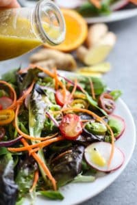 Ginger-Sesame Vinaigrette being poured over salad