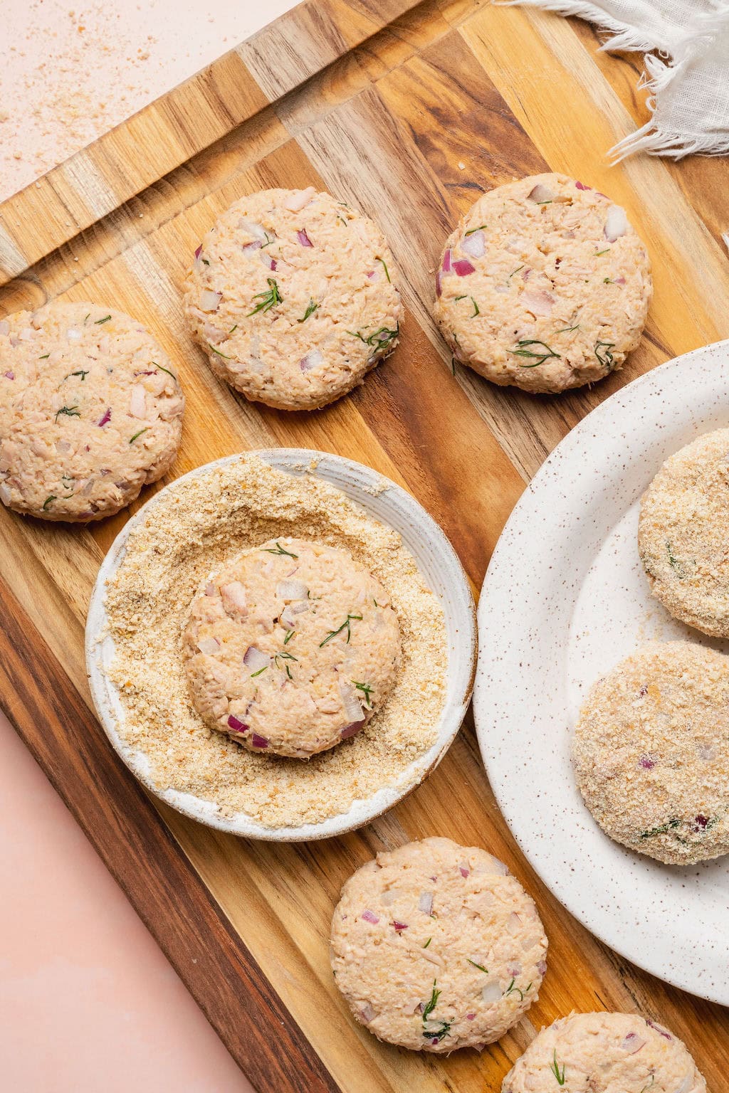 Tuna patties being breaded in a small bowl.