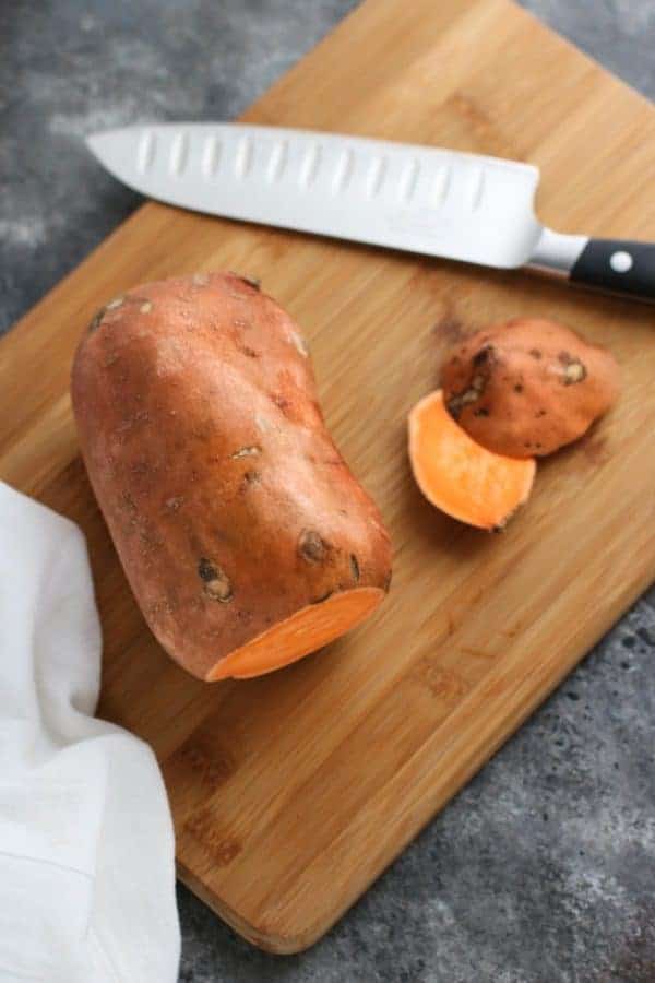 Oven Baked Sweet Potato Toast 4 Ways sweet potato on a wooden cutting board with a knife