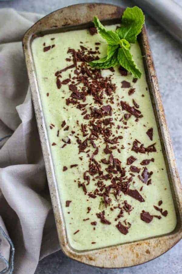 Dairy-free Mint Chocolate Chip Ice Cream in a silver pan with a mint leave garnish in the corner