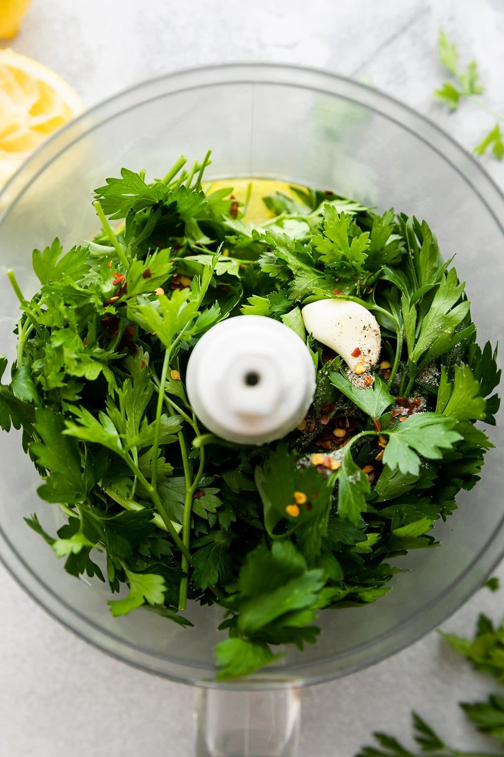 Overhead view food processor bowl filled with greens for chimichurri sauce