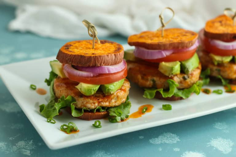 Close up side view buffalo chicken sliders in roasted sweet potato buns on tray