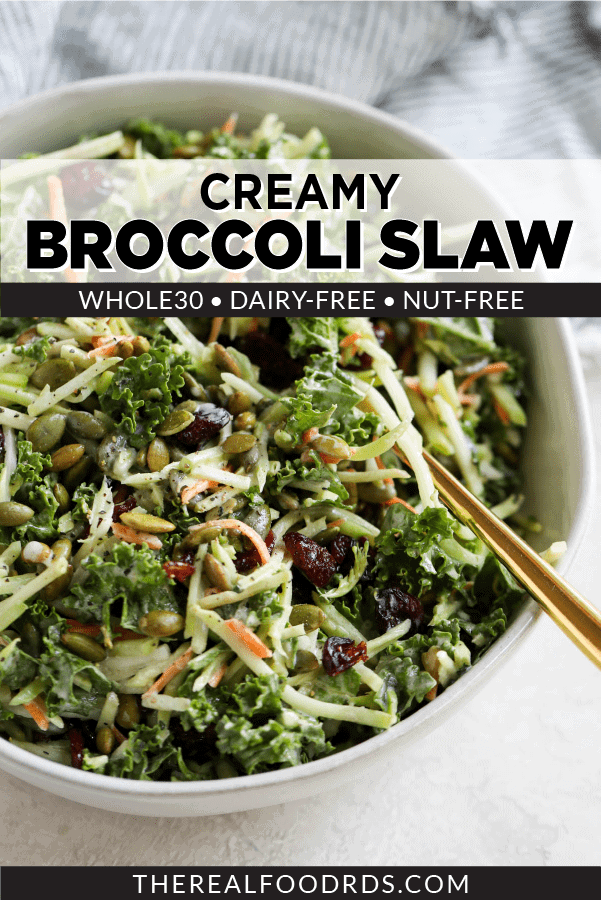 Broccoli Slaw made with homemade dressing and dried cranberries in a white bowl with gold serving spoon.