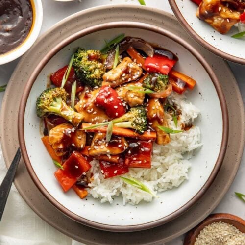 A bowl of white rice topped with sheet pan teriyaki chicken and vegetables.