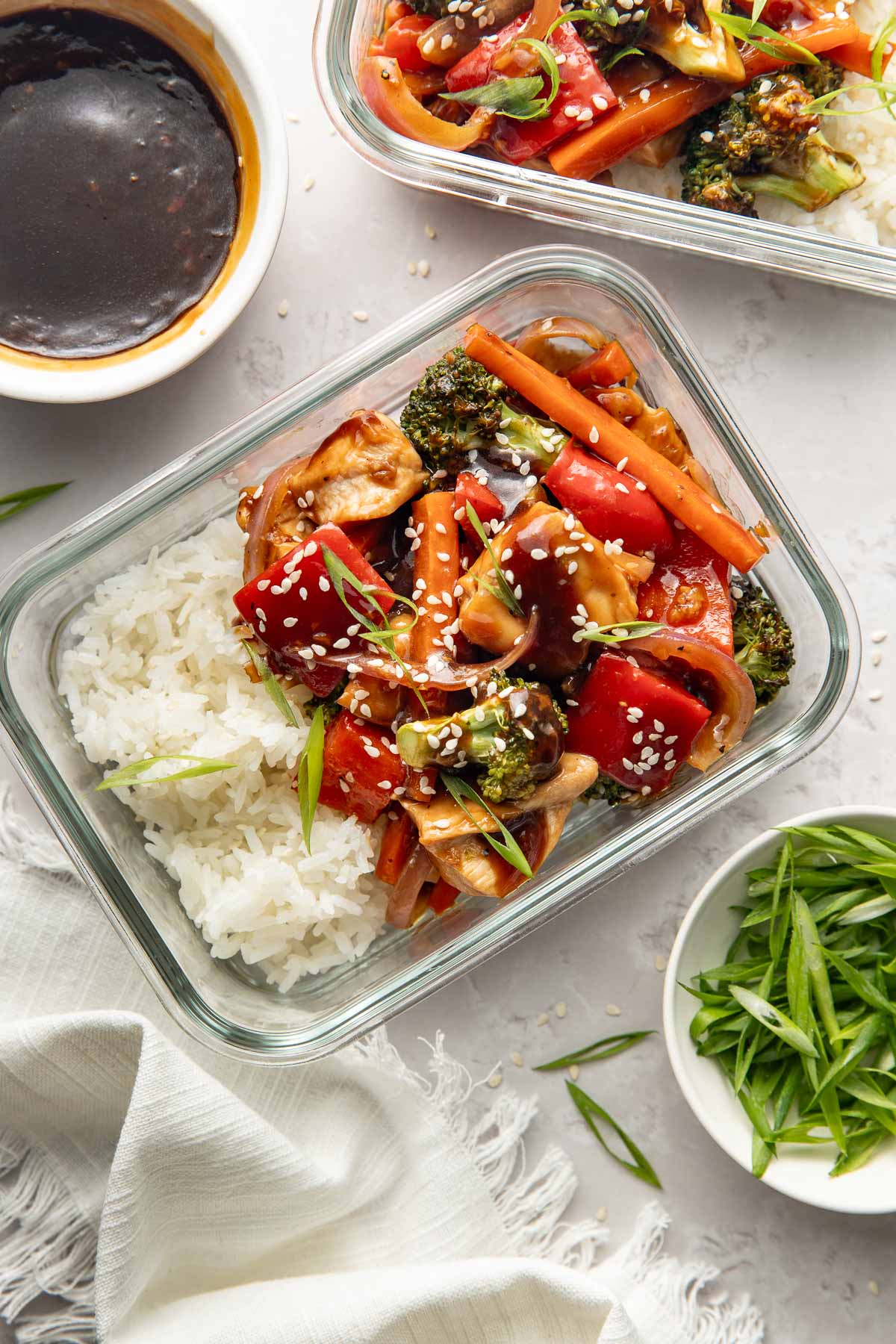 Two meal prep containers with white rice and sheet pan teriyaki chicken and vegetables.