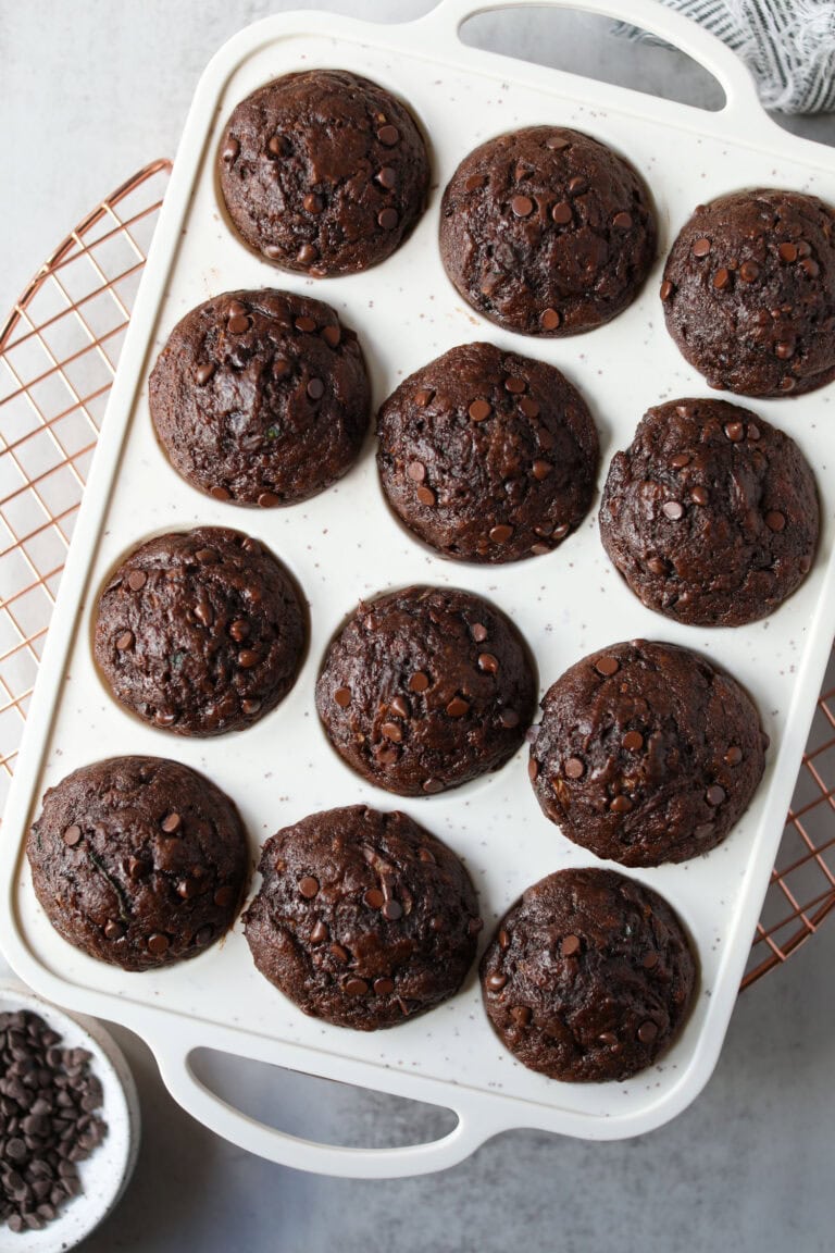 Overhead view of a muffin pan filled with freshly baked chocolate zucchini muffins. 