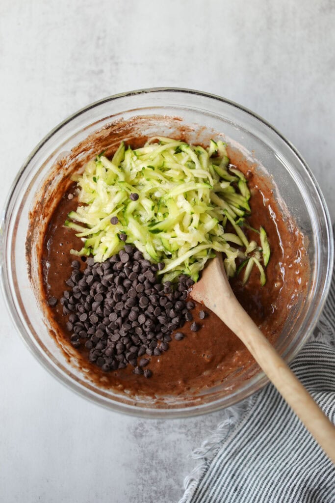 Overhead view of a glass bowl filled with Double Chocolate Zucchini Muffin batter ready for stirring. 