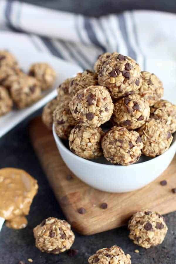 Peanut butter chocolate chip energy bites piled in a white bowl on a cutting board