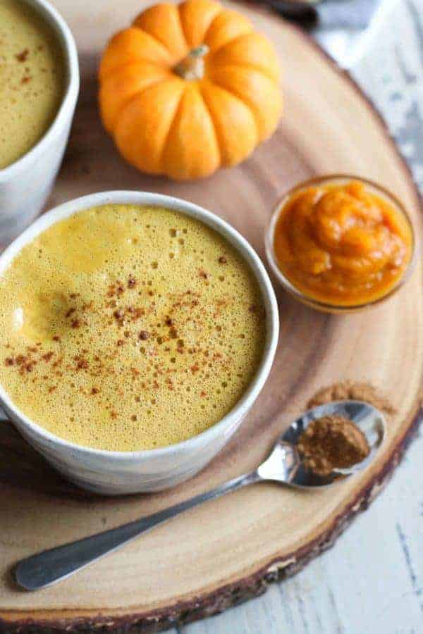 Pumpkin Spice Butter Coffee in a white mug with pumpkins on the side on a wooden cutting board