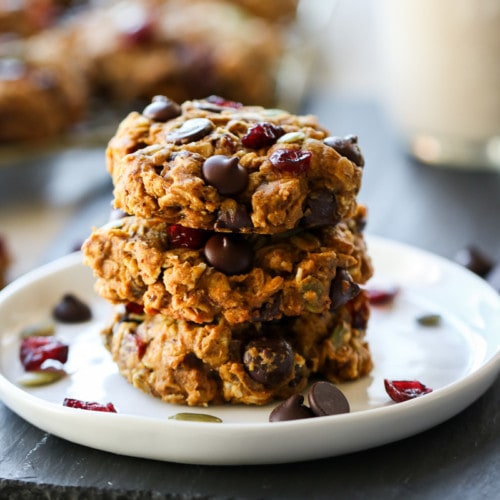 Three healthy oatmeal breakfast cookies stacked up on a white plate.