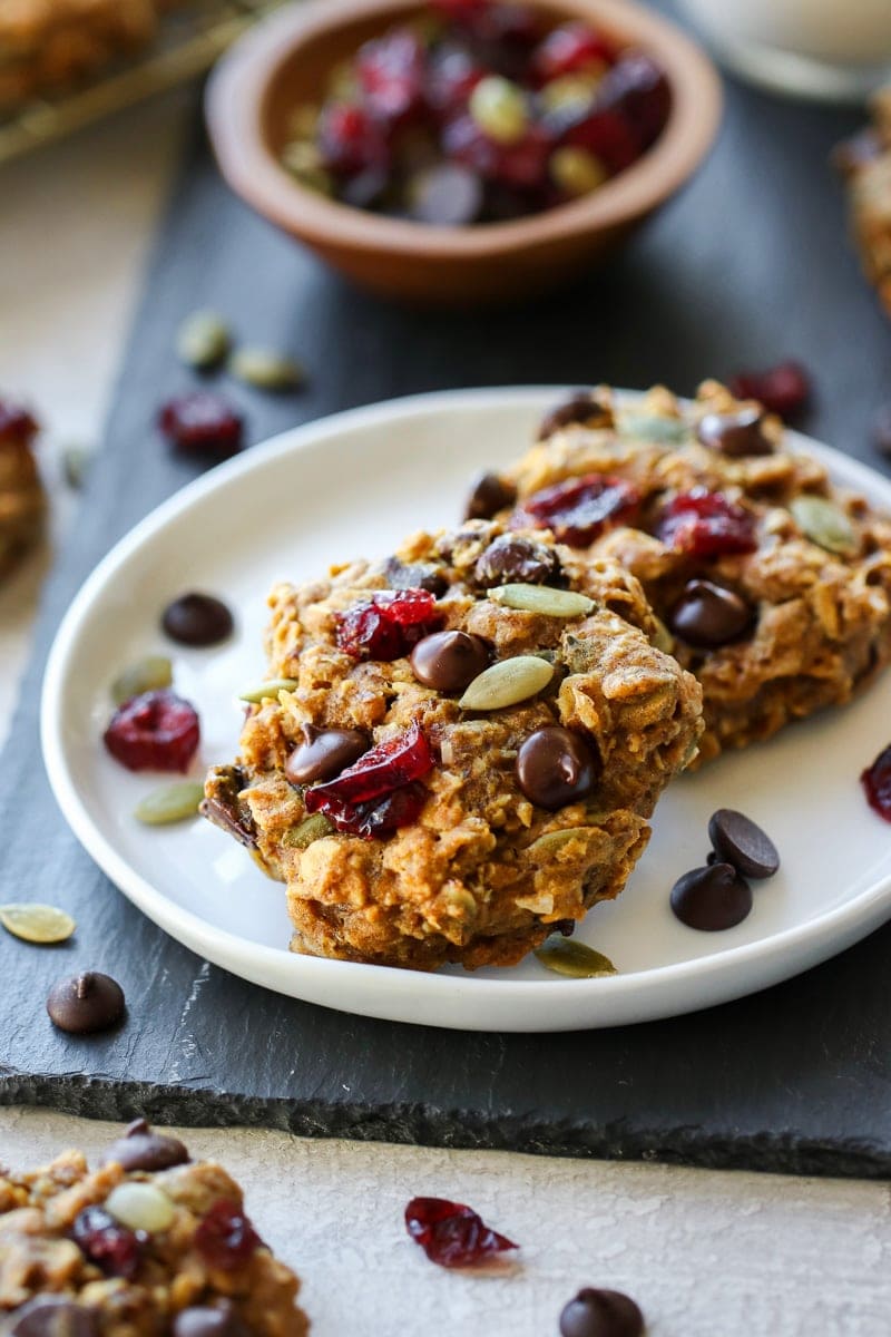 Two healthy pumpkin breakfast cookies studded with dark chocolate chips on a white plate.