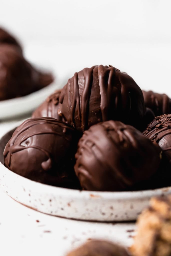 Close up view of chocolate coated chocolate chip cookie dough bites in a shallow bowl