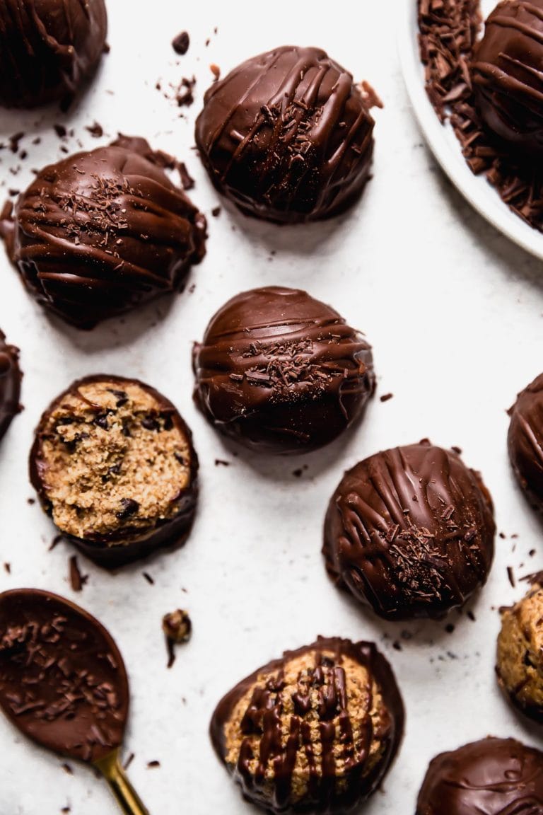 Overhead view of chocolate chip cookie dough bites covered in chocolate arranged together on a counter