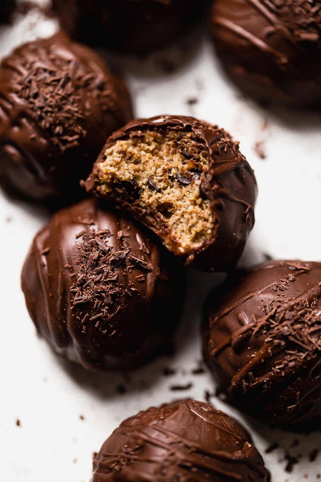 Chocolate Chip Cookie Dough Bites scattered about with one having a bite out of it showing the center.