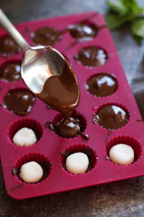 chocolate being drizzled on top of mint in the mold