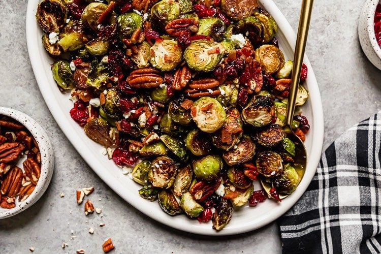 Roasted brussels sprouts with bacon and dried cranberries on a white serving platter
