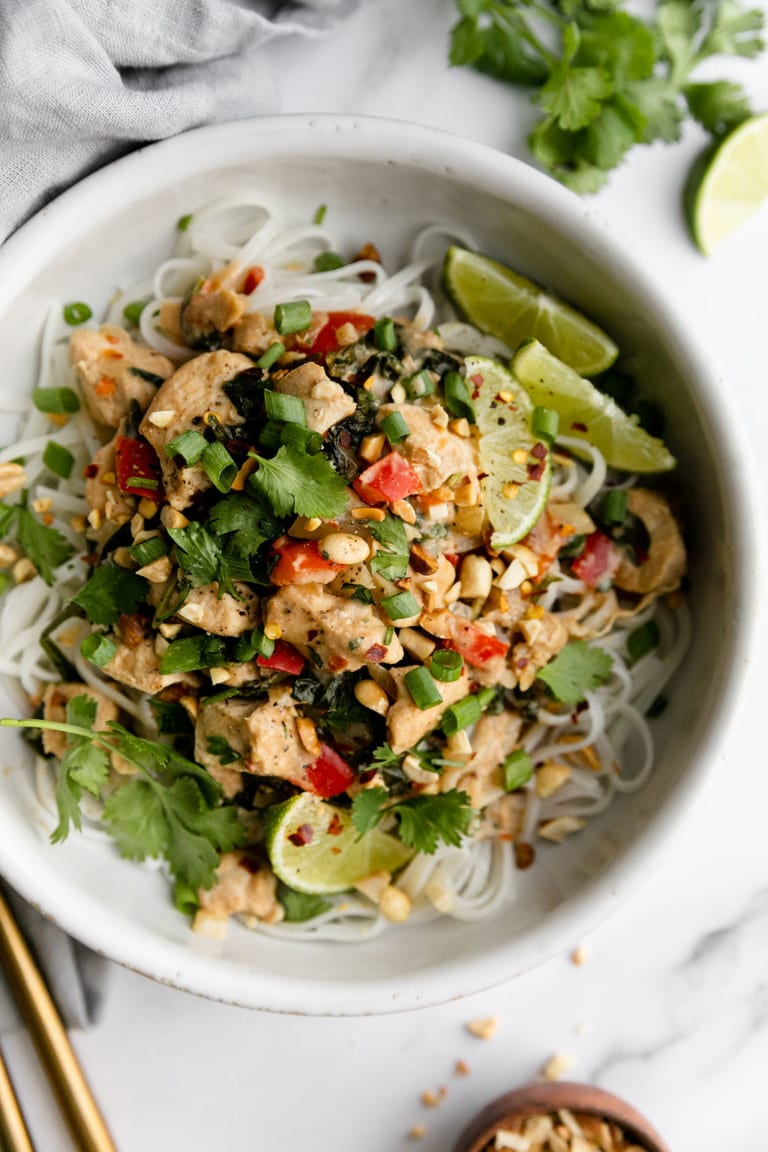 Overhead view slow cooker Thai Peanut Chicken served over rice noodles in bowl
