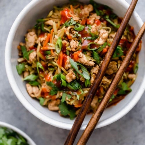 Overhead view white bowl filled with egg roll in a bowl recipe, chop sticks resting on edge of bowl