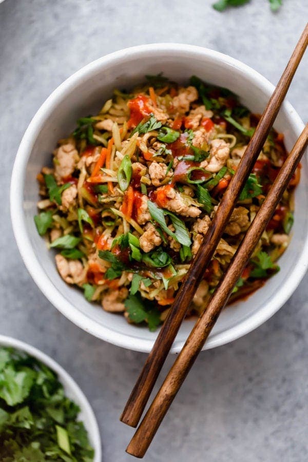 Overhead view white bowl filled with egg roll in a bowl recipe, chop sticks resting on edge of bowl