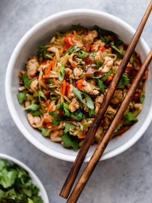 Overhead view white bowl filled with egg roll in a bowl recipe, chop sticks resting on edge of bowl