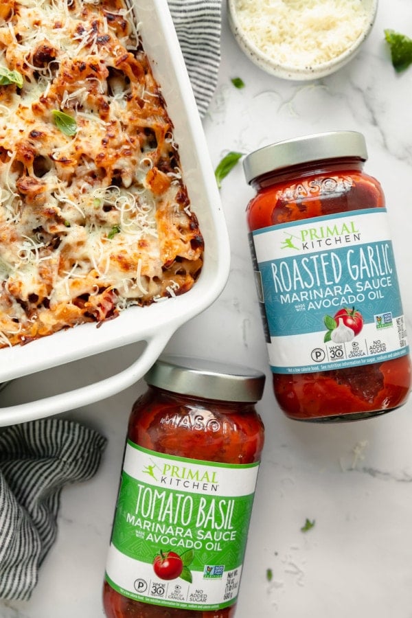 Overhead view two jars spaghetti sauce with Primal Kitchen label next to white casserole dish