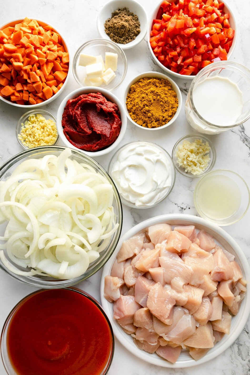 All ingredients for crockpot butter chicken arranged in small bowls.