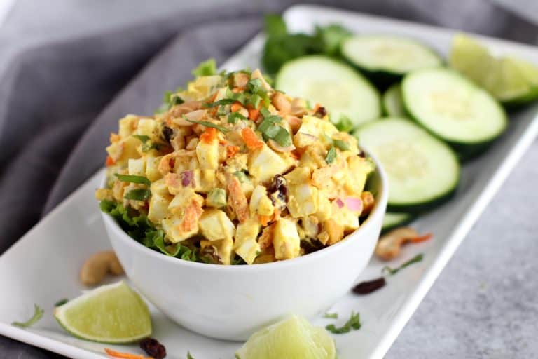 A heaping bowl of curry egg salad topped with fresh herbs. 