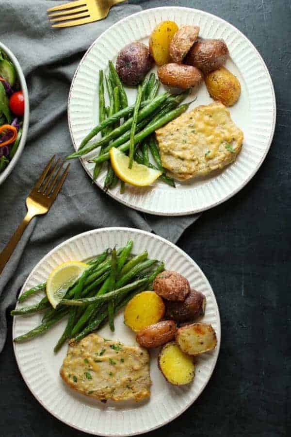 Two plates of food with honey mustard pork chops, potatoes and green beans.