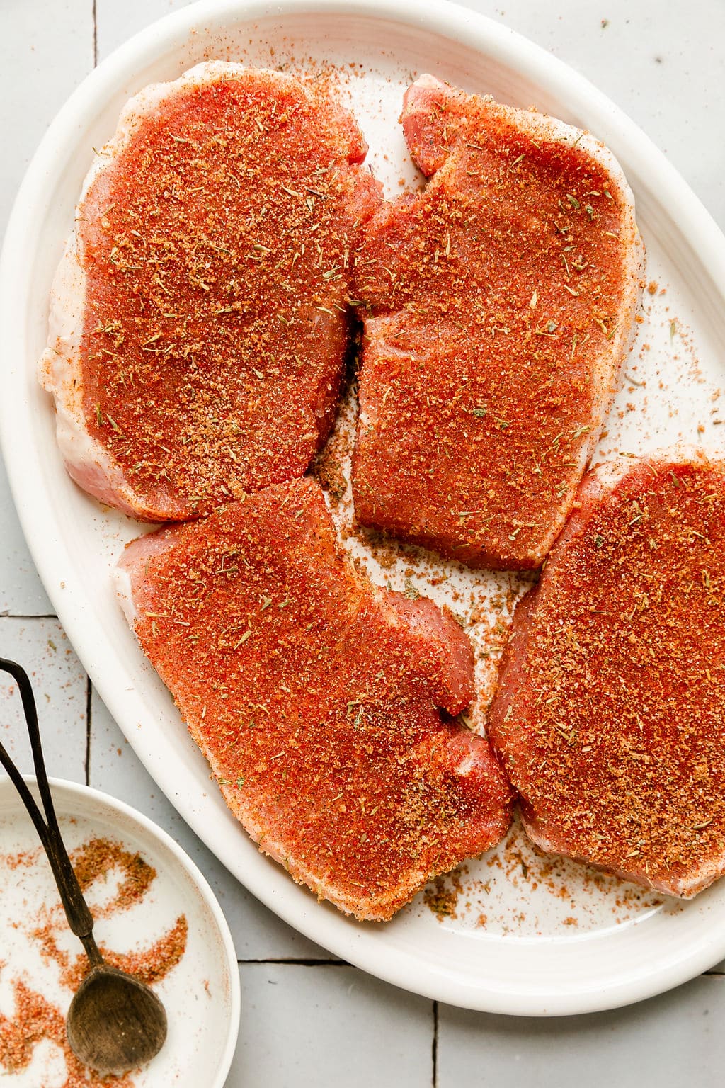 Overhead view seasoned raw pork chops on platter