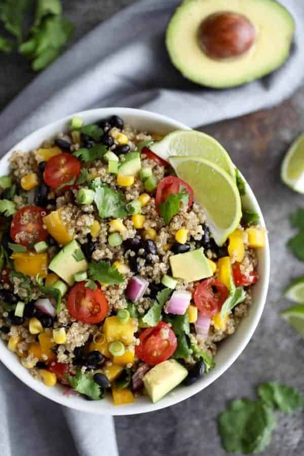 Tex-Mex Quinoa Salad in a white bowl with an avocado on the side