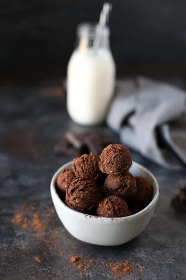 no-bake brownie bites in a white bowl with a glass of milk 