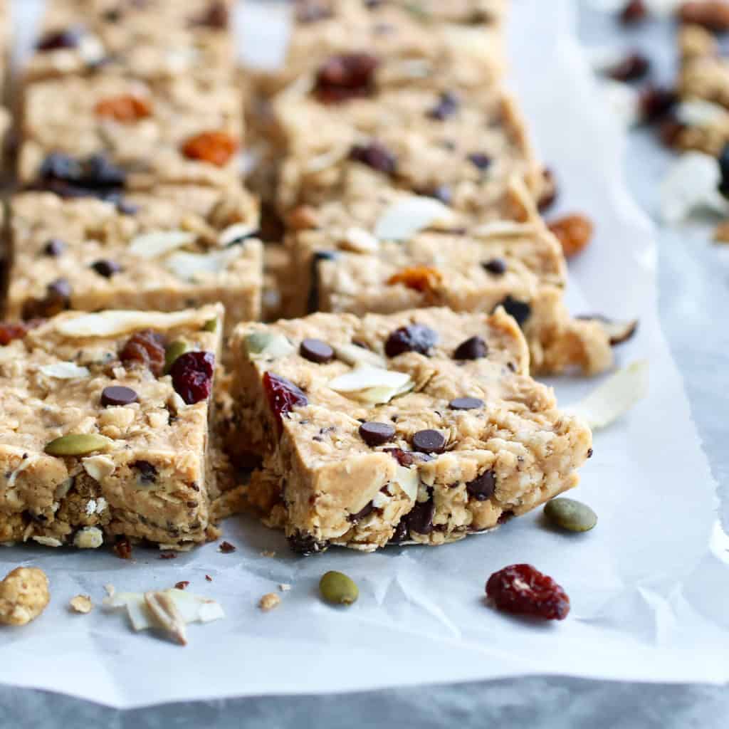 A row of cut fruit and nut granola bars lined up on parchment paper
