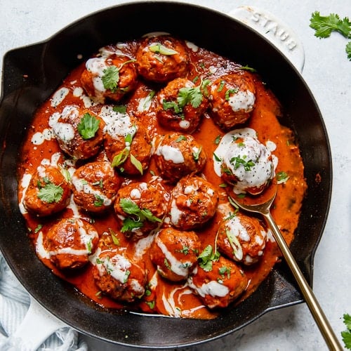 Buffalo chicken meatballs in a cast iron skillet drizzled with ranch