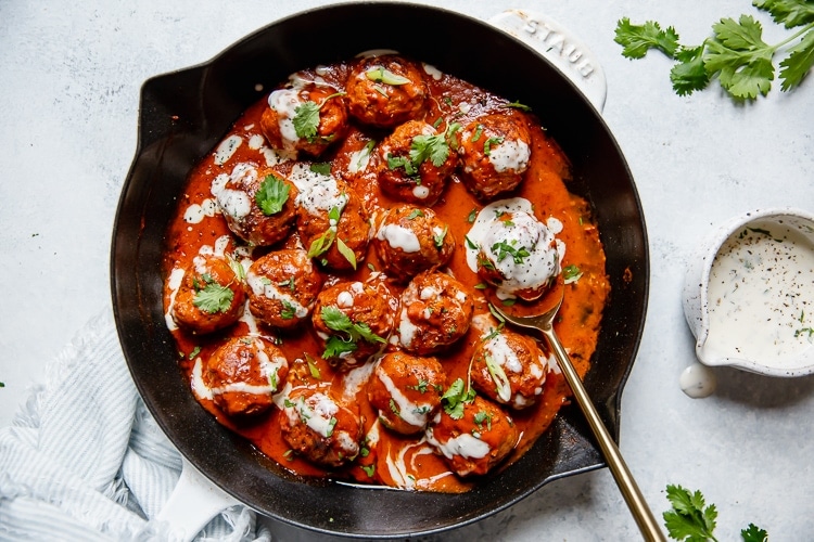 Buffalo chicken meatballs in a cast iron skillet drizzled with ranch