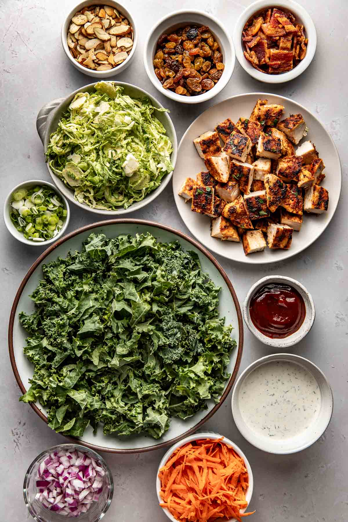 Overhead view of a variety of ingredients for Chopped BBQ Ranch Chicken Salad in different sized bowls. 