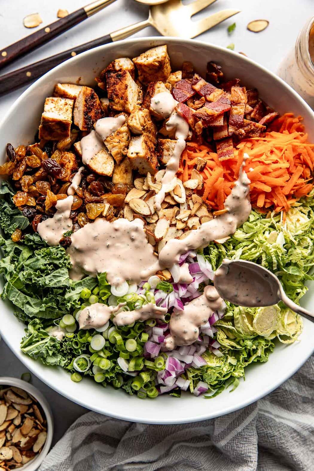 Overhead view of a white bowl filled with Chopped BBQ Ranch Chicken Salad with different ingredients arranged in sections ready to be stirred. 