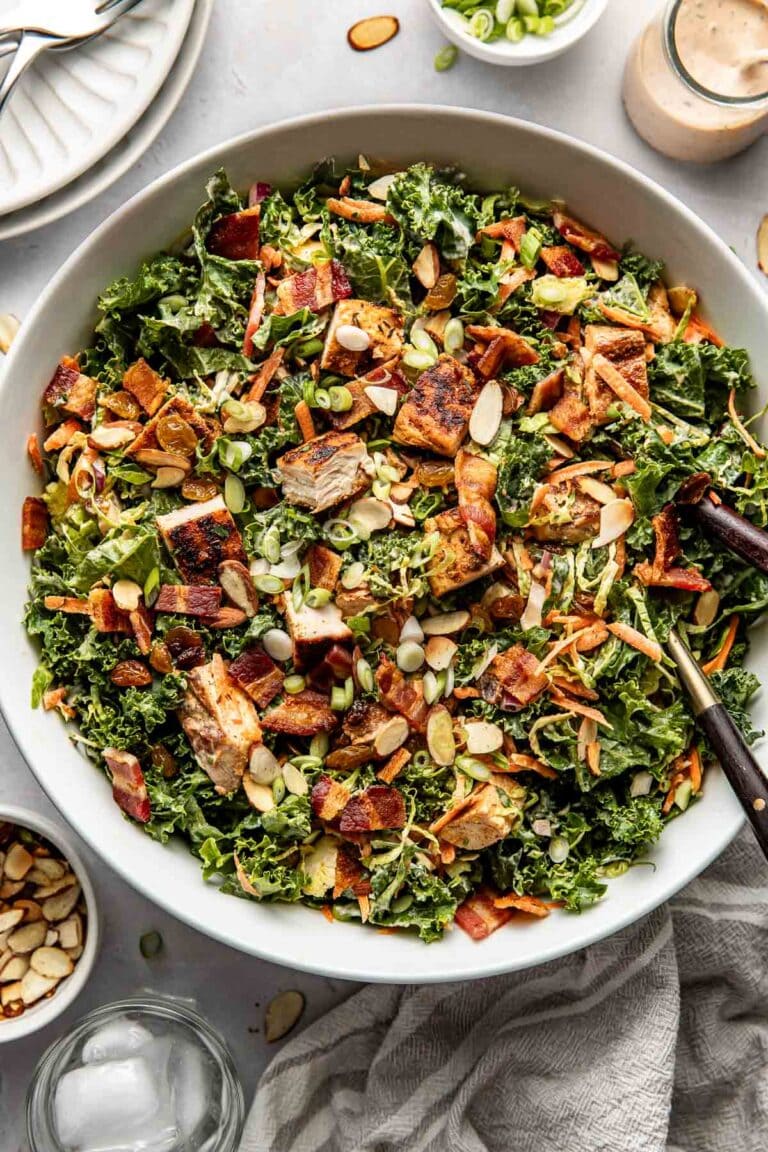 Overhead view of a serving bowl of BBQ Ranch chopped chicken salad with toasted almonds on top and pieces of chopped blackened chicken visible.