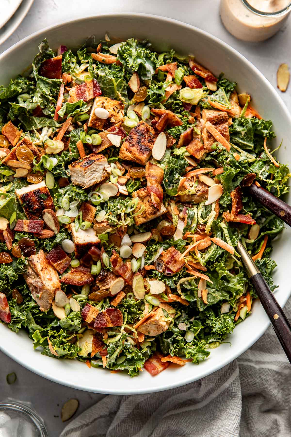 Overhead view of a white bowl of Chopped BBQ Ranch Chicken Salad topped with green onions and toasted almond slices. 