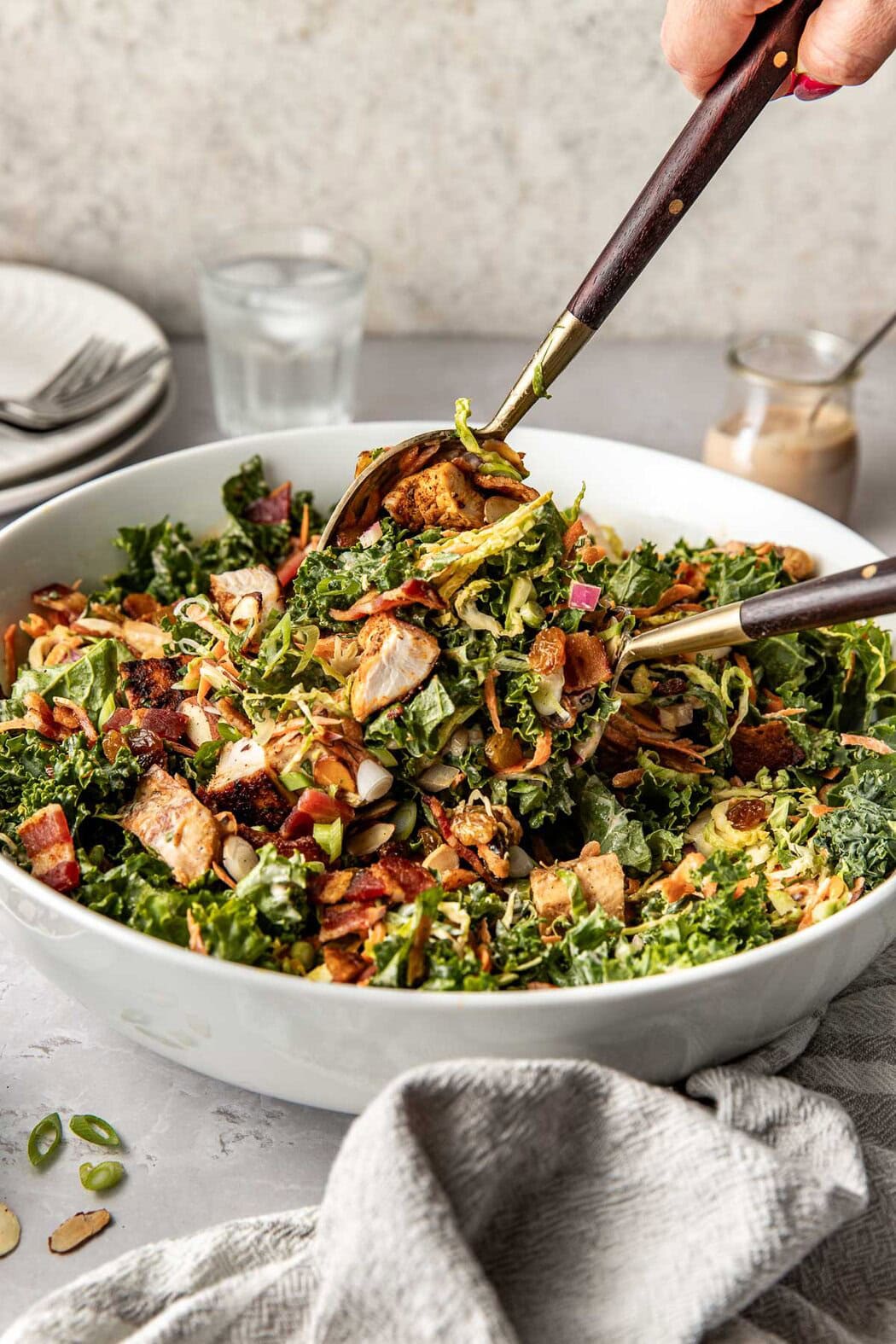 Close up view of two spoons tossing a colorful Chopped BBQ Ranch Chicken Salad in a white bowl. 