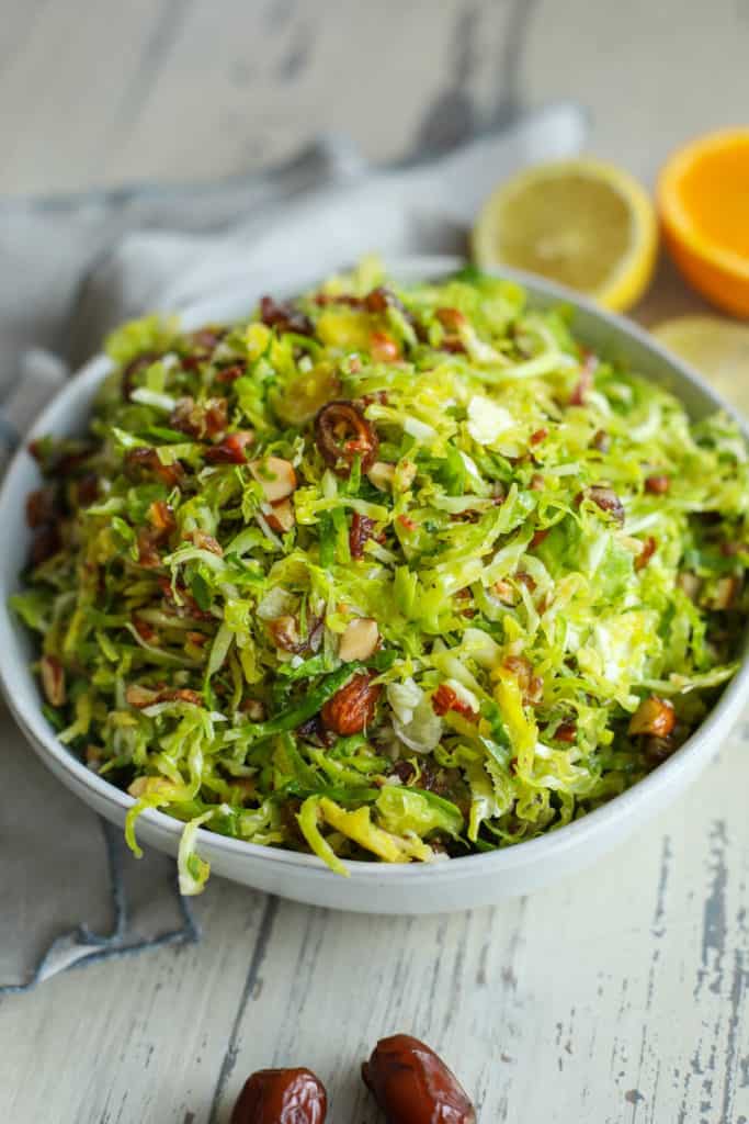 Sweet and smoky Brussels slaw with dates in a serving bowl.