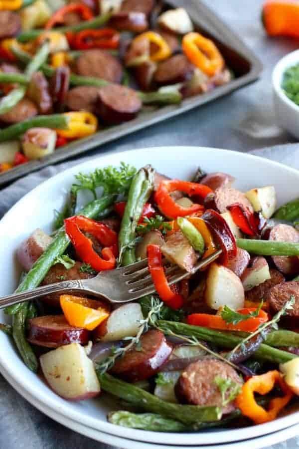 One-Pan Kielbasa Veggie Bake in a white bowl with a silver fork 